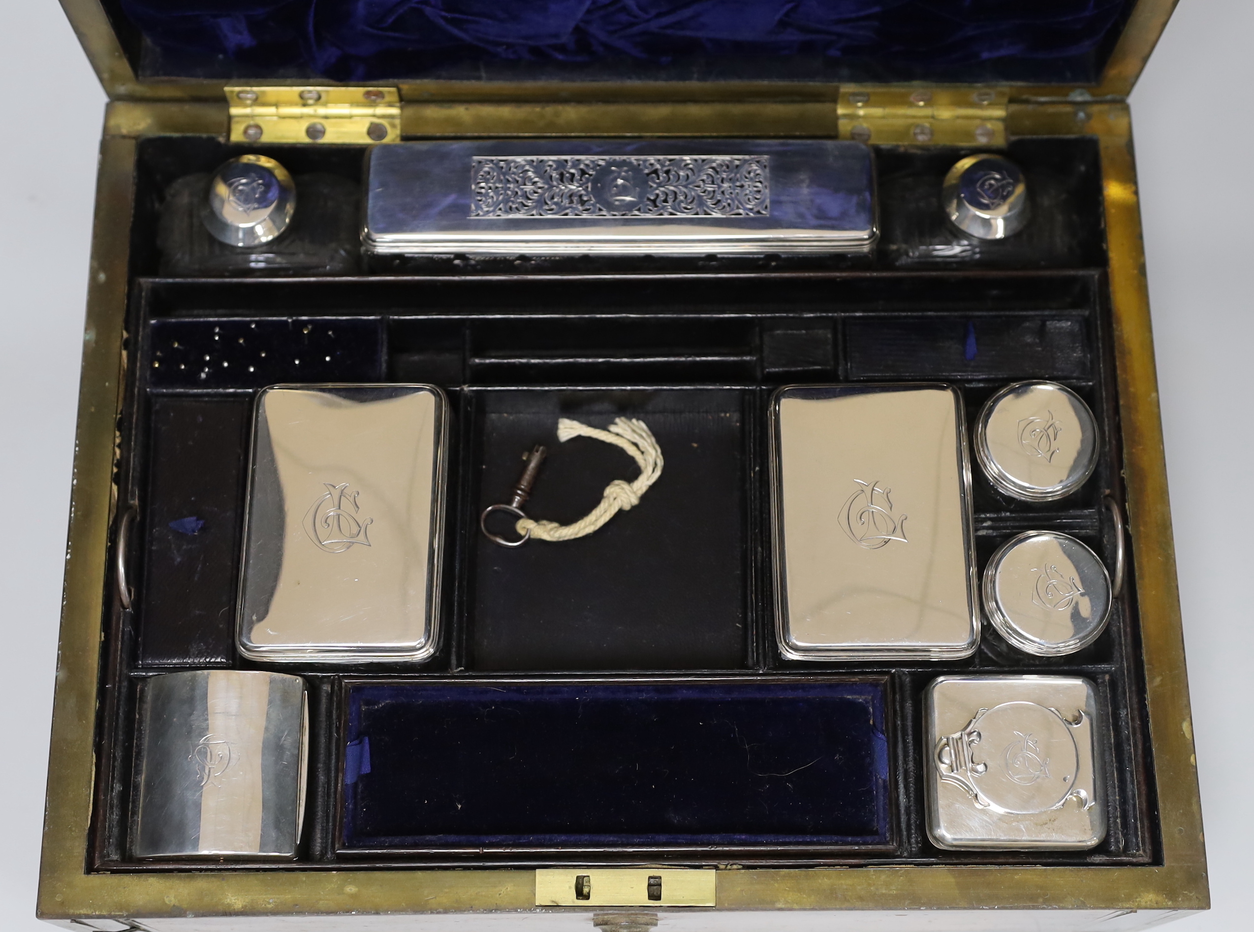 A George IV brass mounted rosewood travelling toilet box, with eleven silver mounted glass toilet jars etc, John & Archibald Douglas, London, 1822, with engraved monograms, four caps unmarked, box 34.1cm.